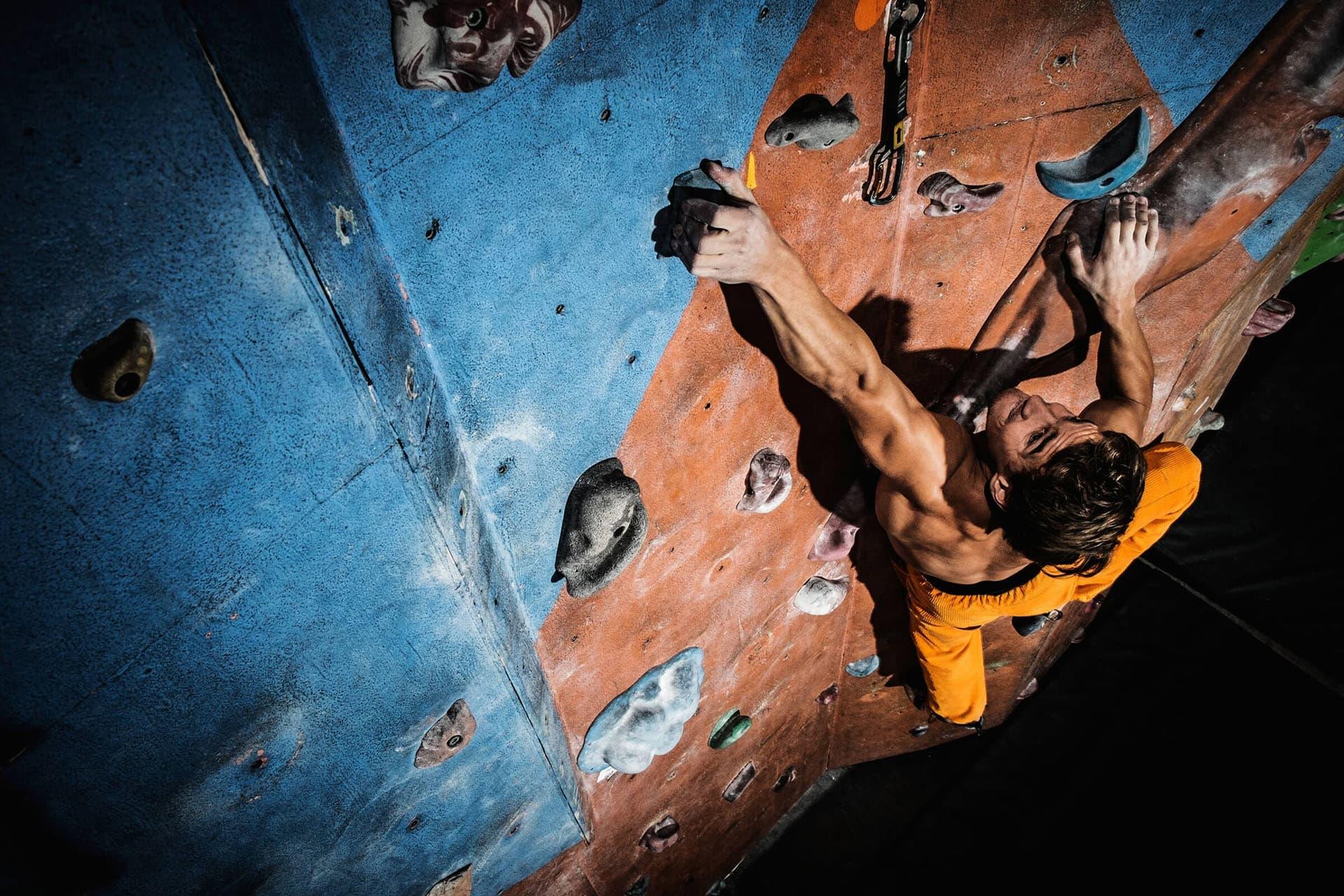 Male rock climber scaling a steep rock wall, demonstrating power and endurance