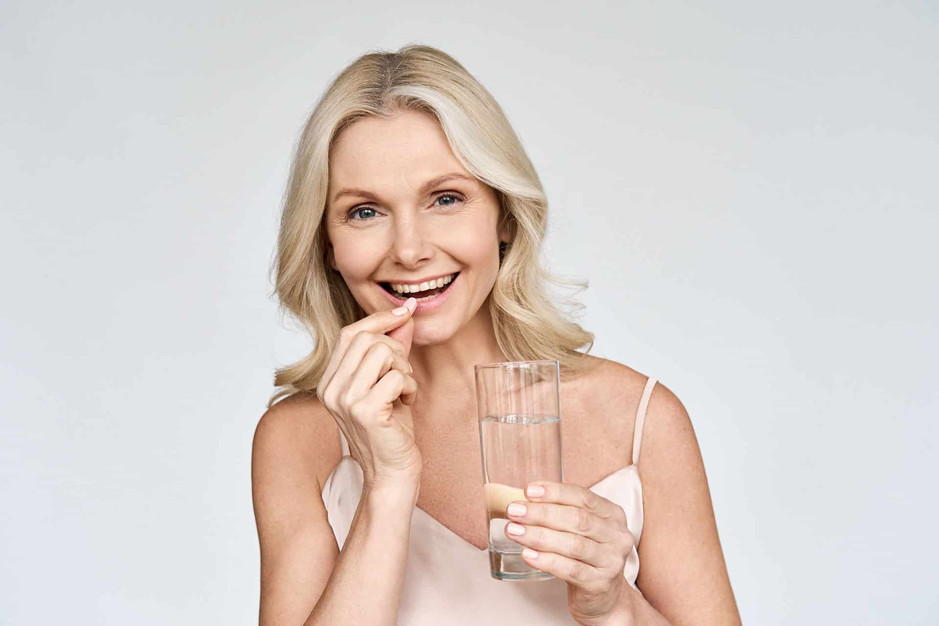 Older woman taking a supplement with a glass of water