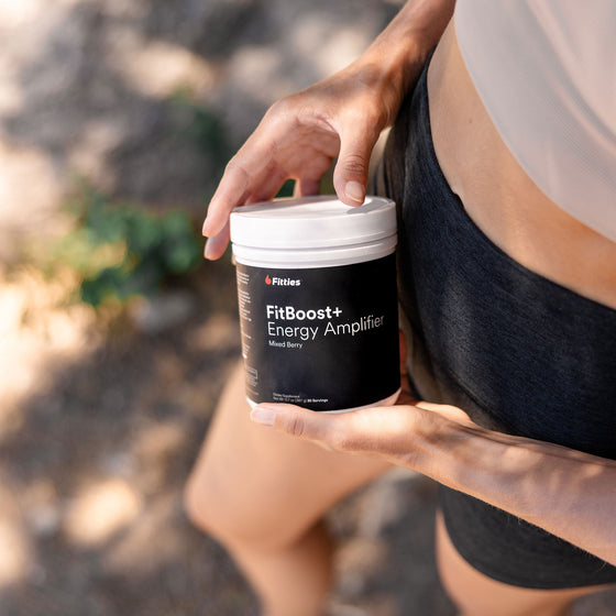 Closeup of fit female athlete holding Fitties FitBoost+ supplement container