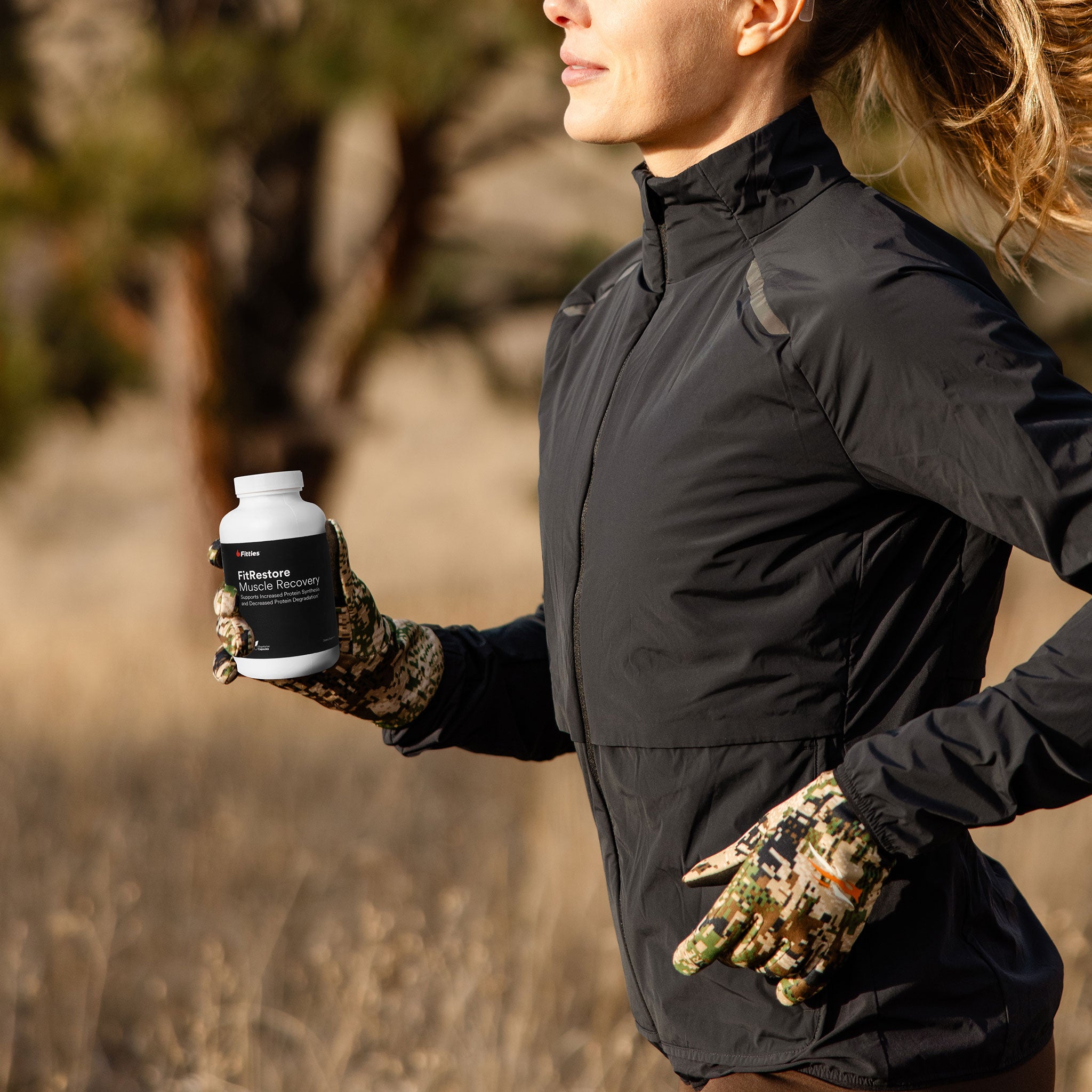 Fitties ambassador running outdoors holding a supplement bottle