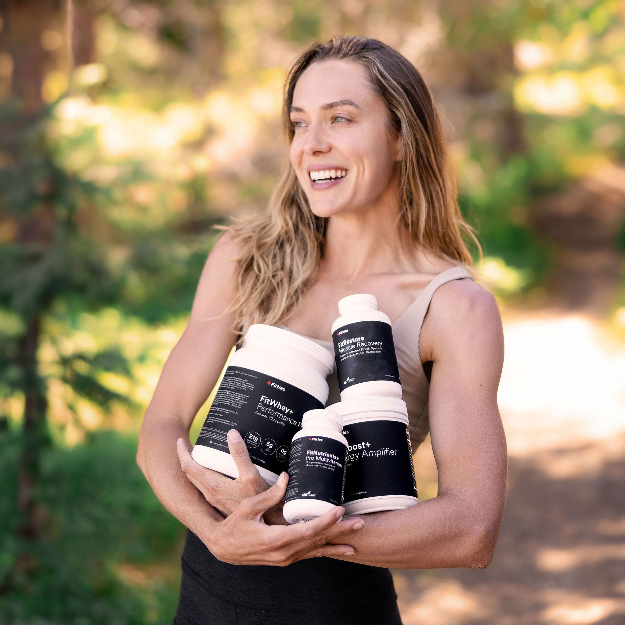 Fitness model holding Fitties Max Muscle Stack in nature