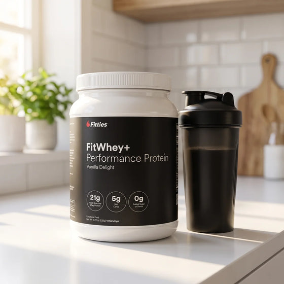 Fitties FitWhey+ grass-fed whey protein tub and shaker bottle on a kitchen counter