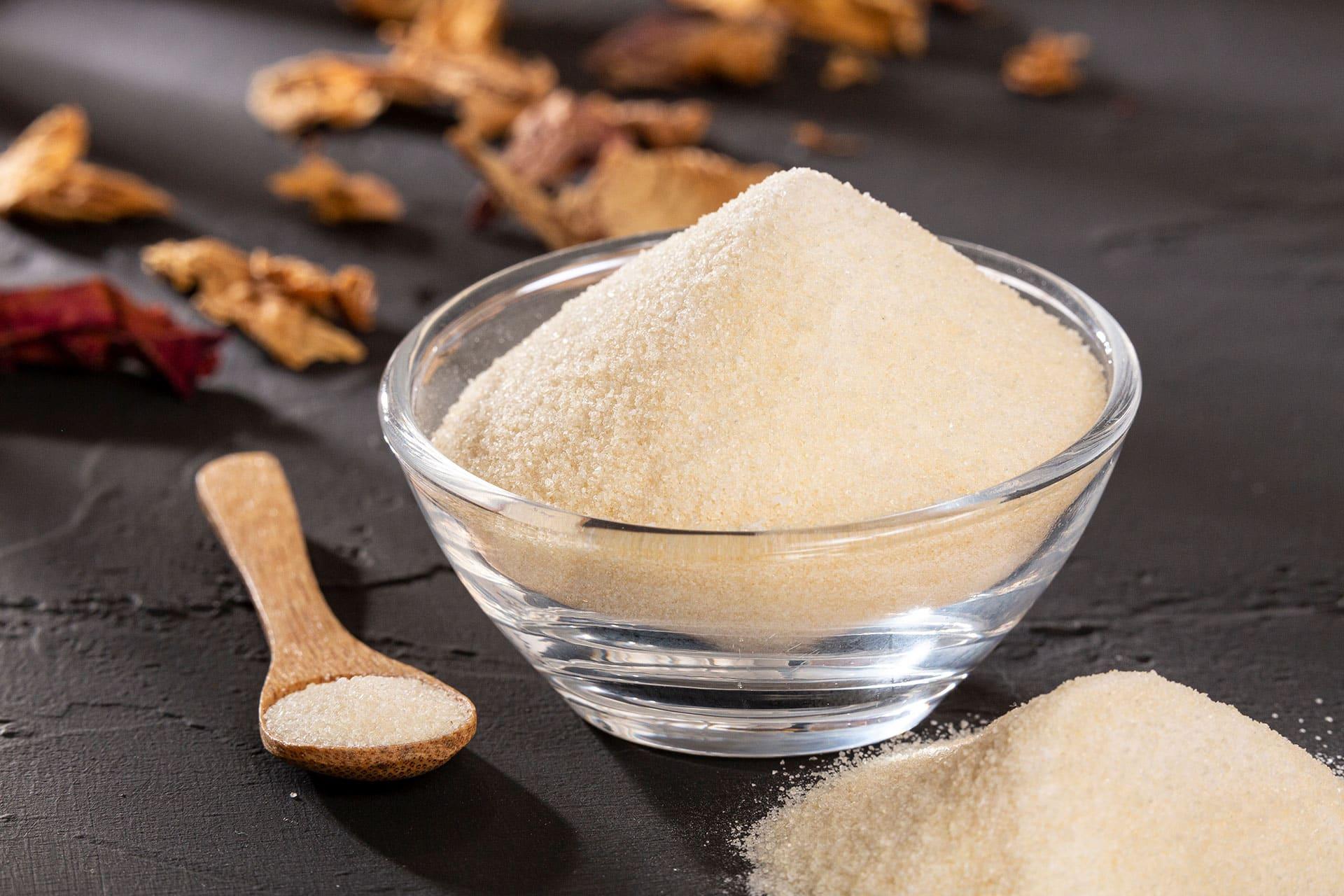 Closeup of bowl of collagen peptide powder on black tabletop