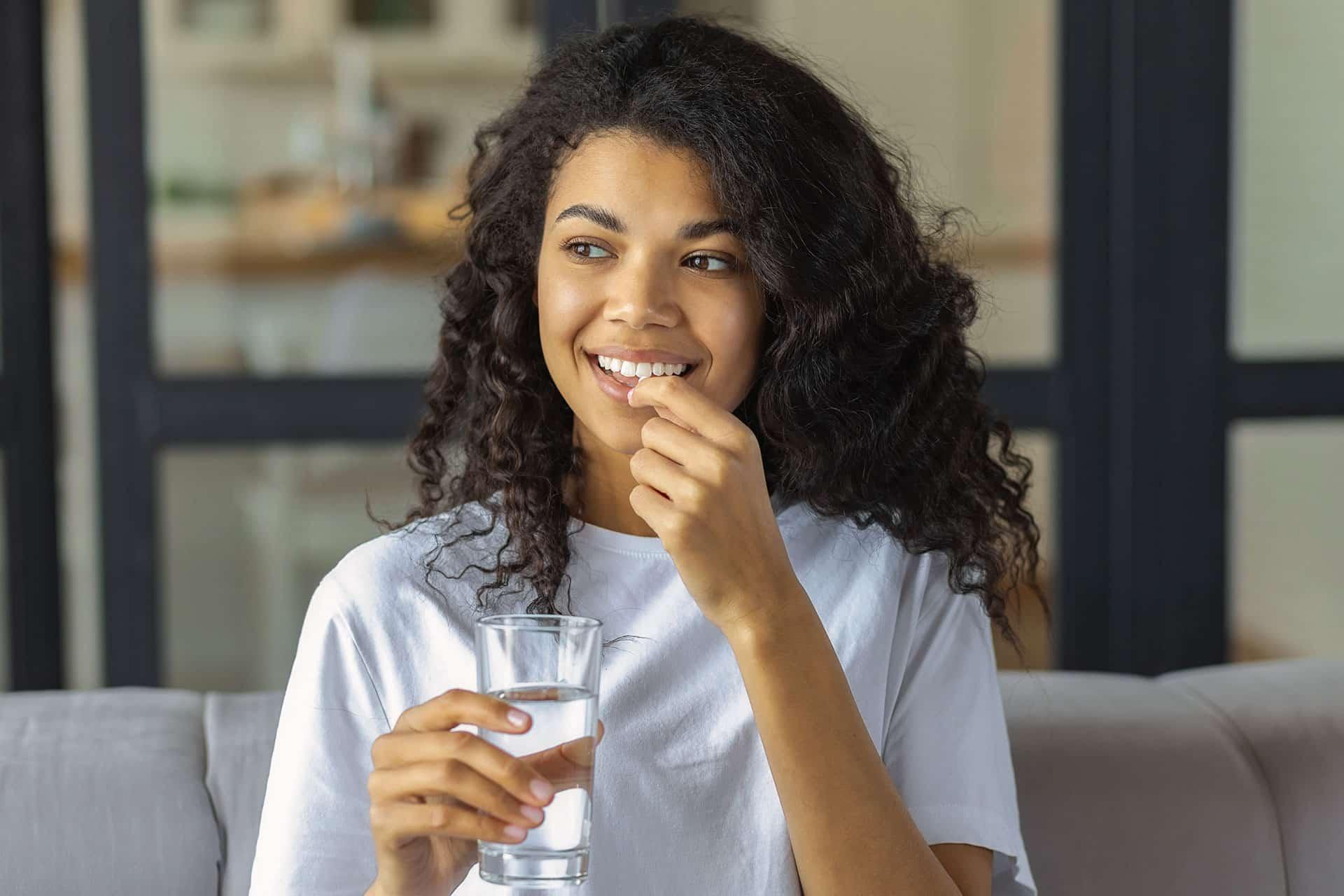 Female smiling while taking supplement tablet