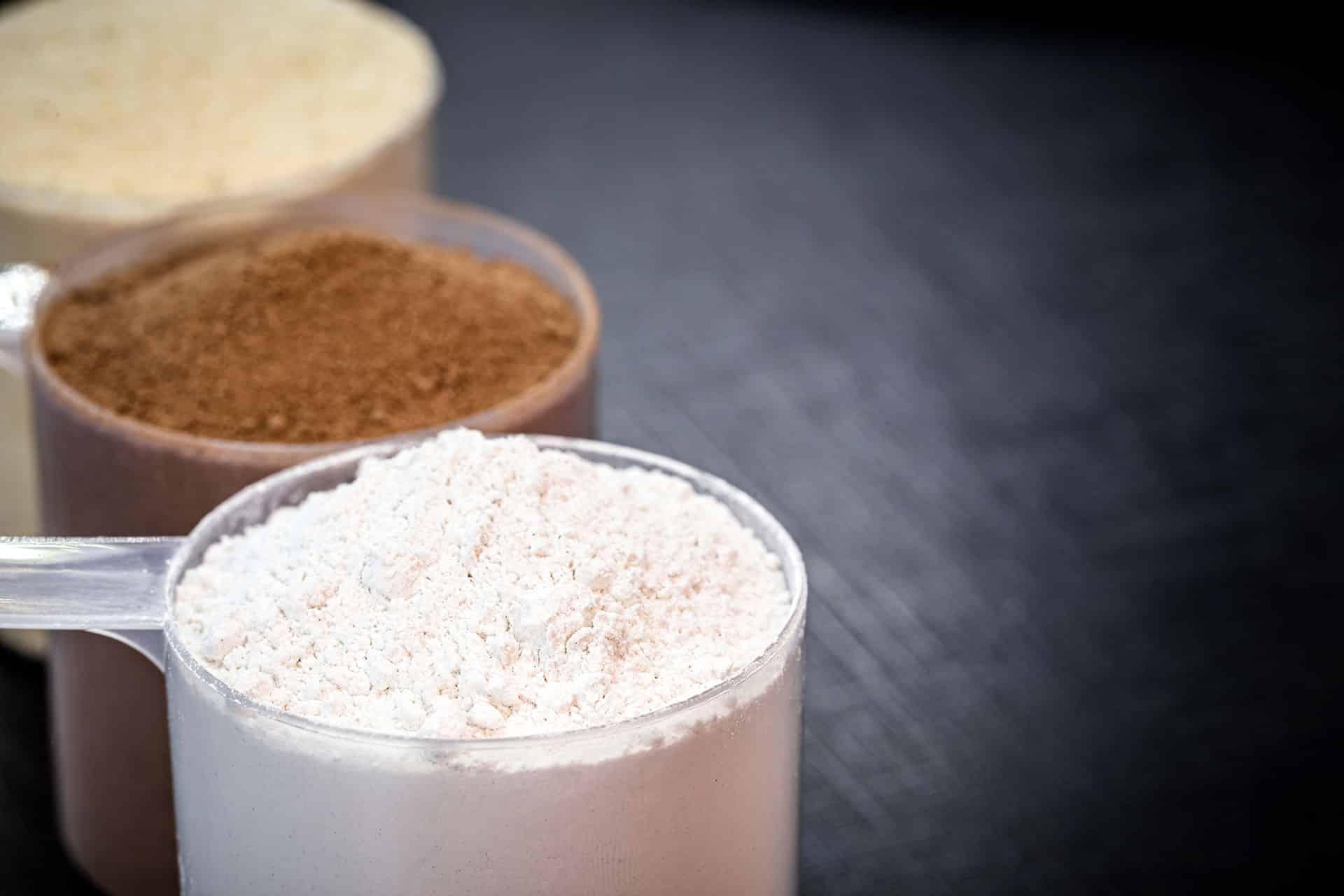 Closeup of three scoops of protein powders in various flavors