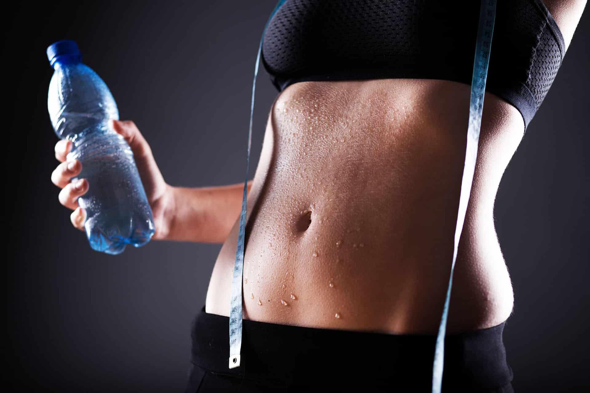 Female in confident pose with water bottle and tape measure