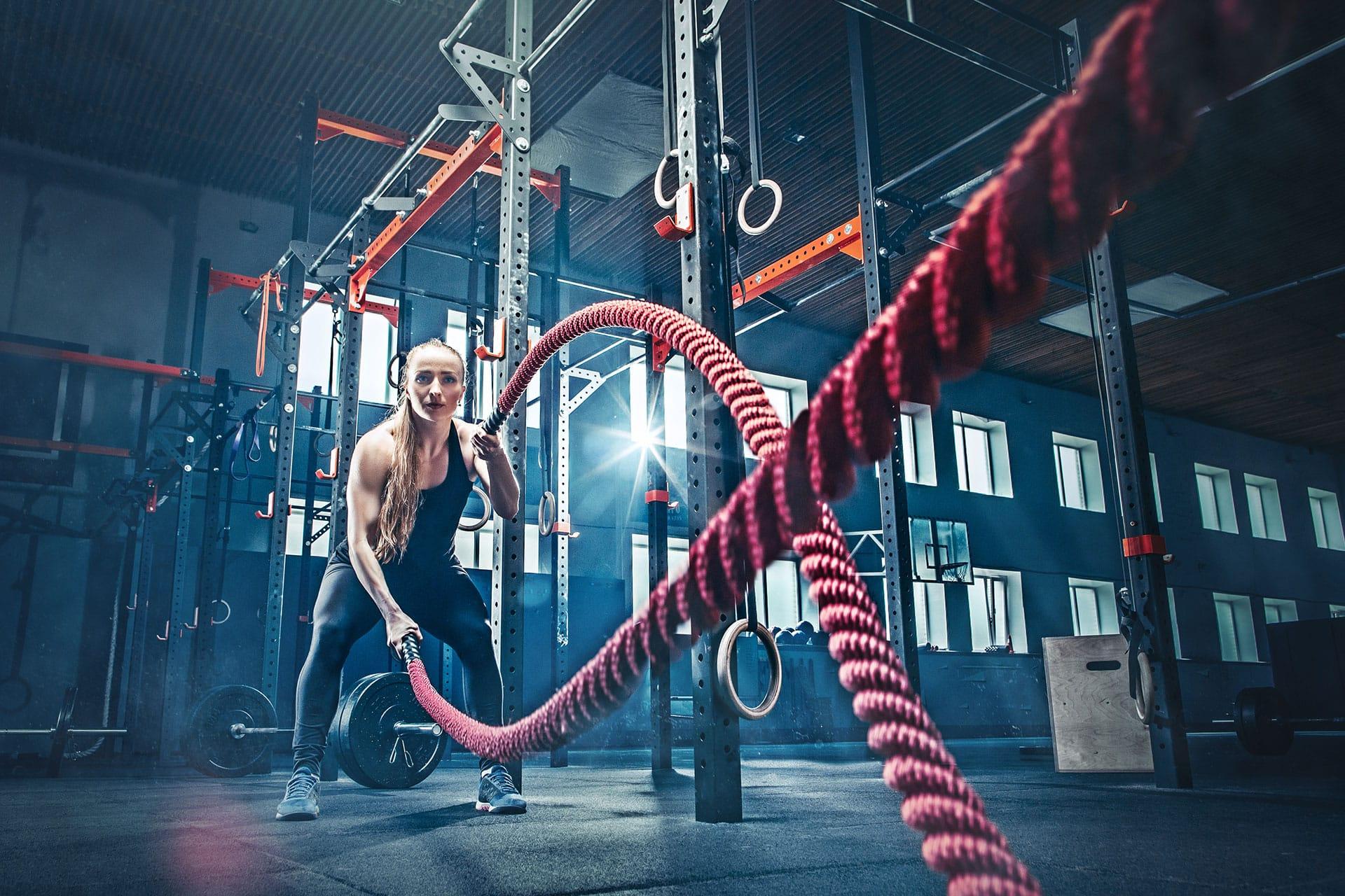 Female performing exercise with battle ropes in gym