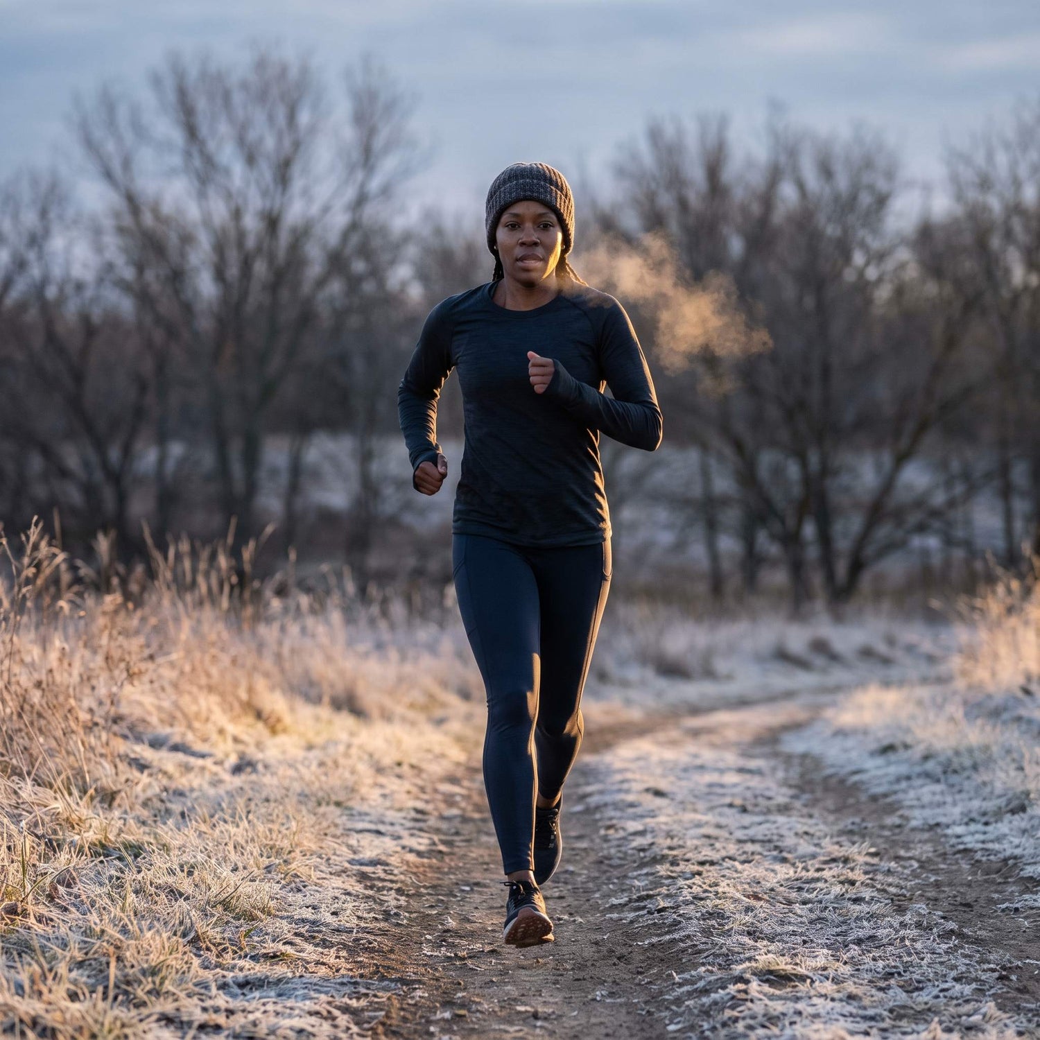 Runner training on a frost-covered trail at sunrise, breath visible in the cold air