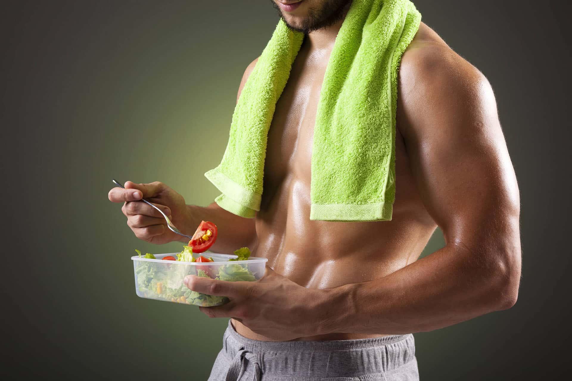 Fit male eating salad over green background
