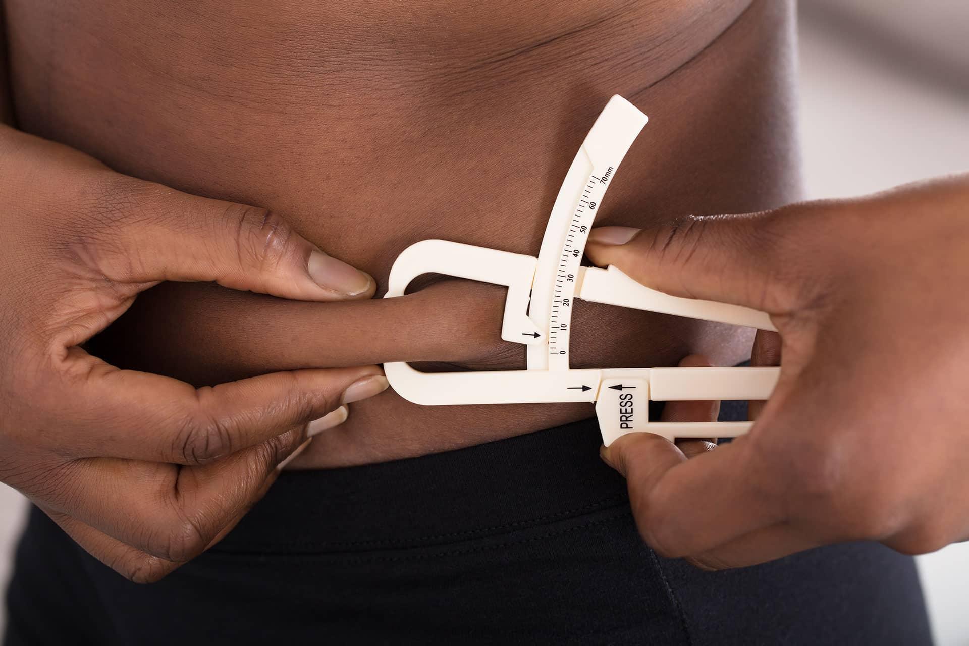 Male measuring skinfold using body fat caliper