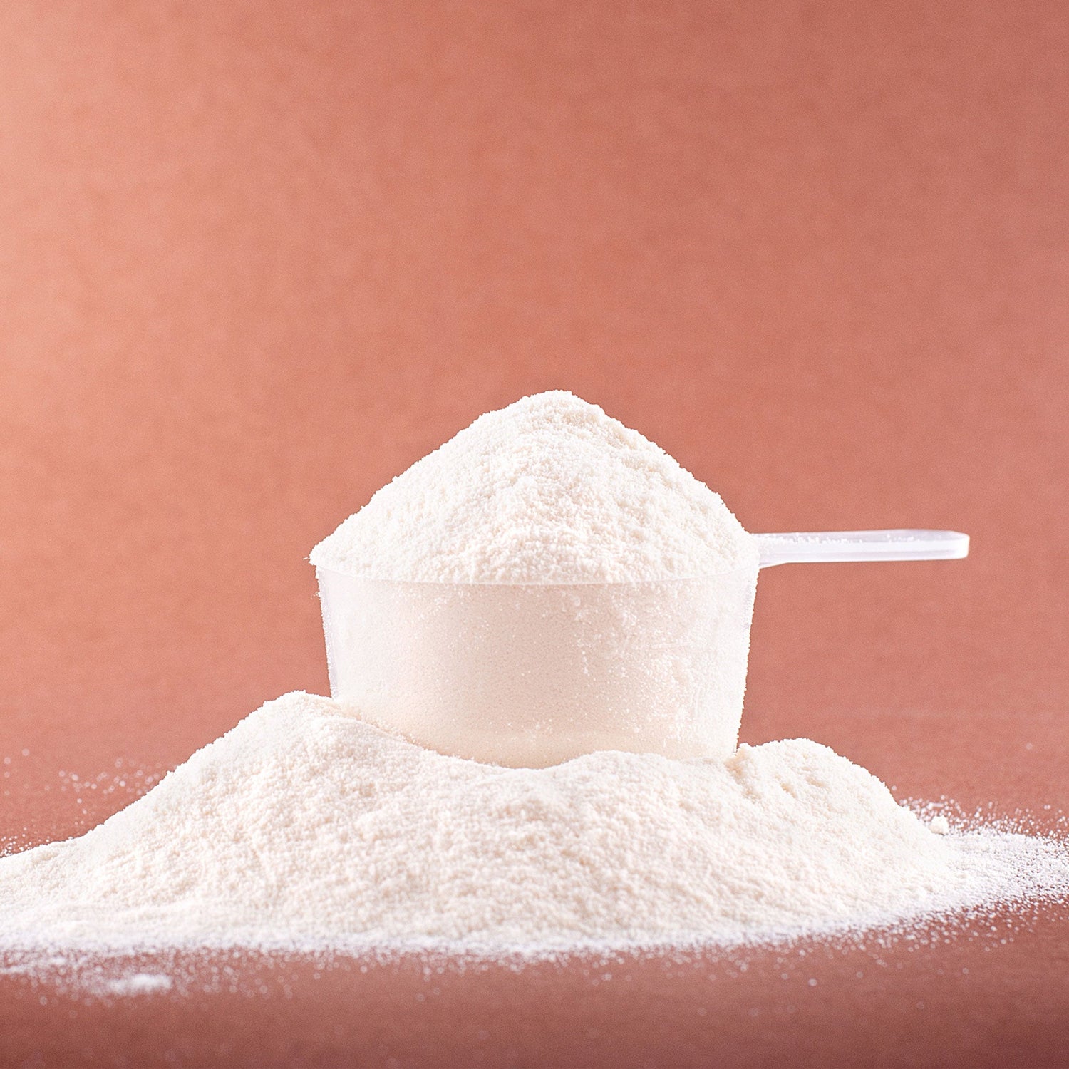 Closeup of a scoop of supplement powder on a plain background