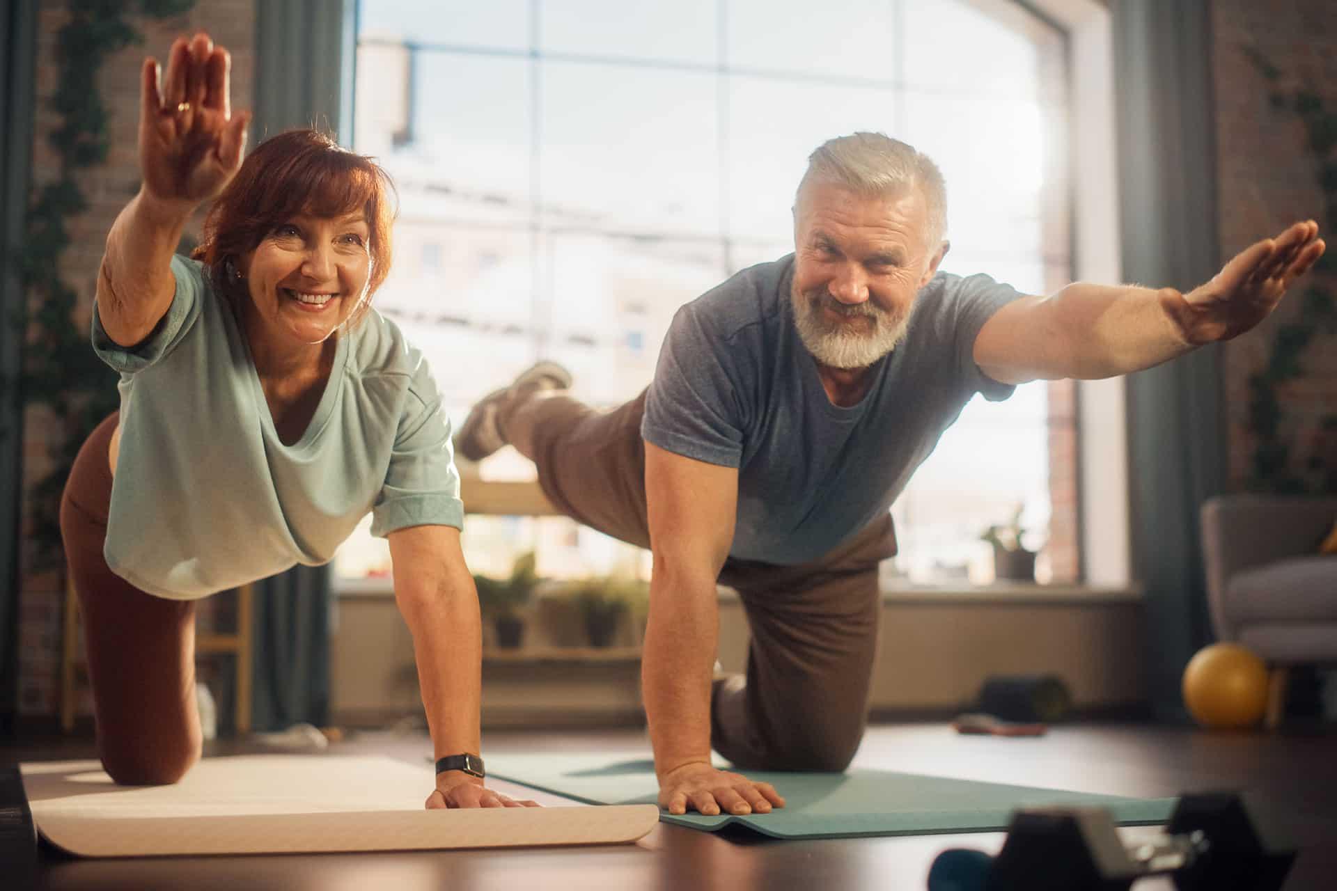 Senior male and female couple performing yoga at home