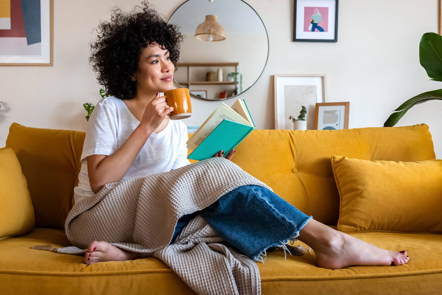 Female relaxing on sofa while reading and enjoying tea
