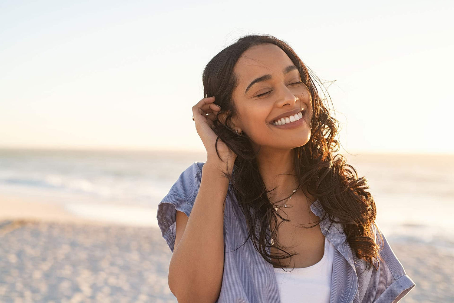 Female smiling in the sunlight while walking on the beach