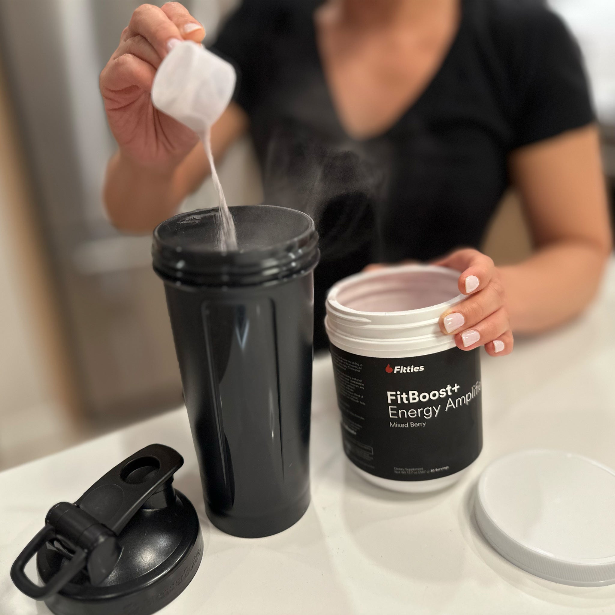 Closeup of female pouring scoop of FitBoost+ in shaker