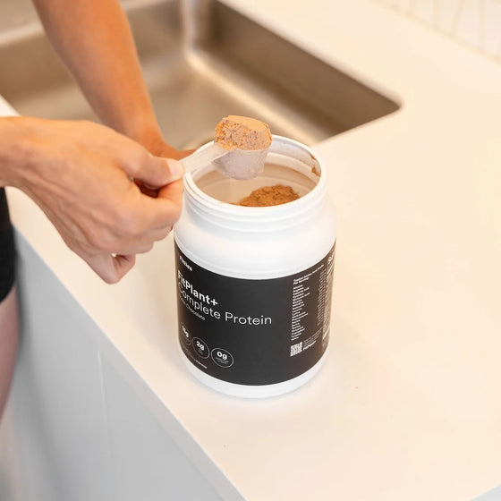 Scooping Fitties FitPlant+ dairy free plant protein powder in a kitchen