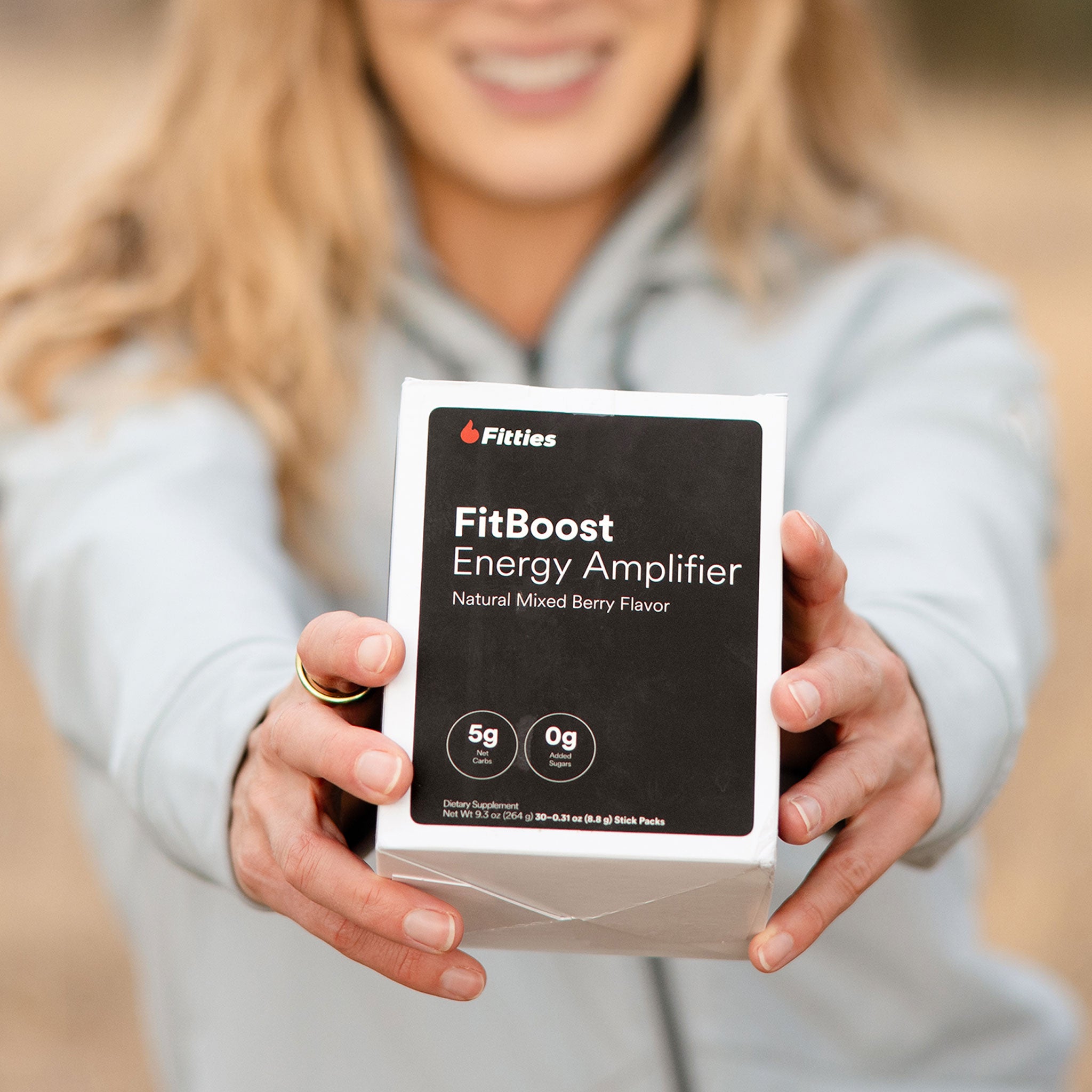 Closeup of fit female athlete holding a box of Fitties FitBoost