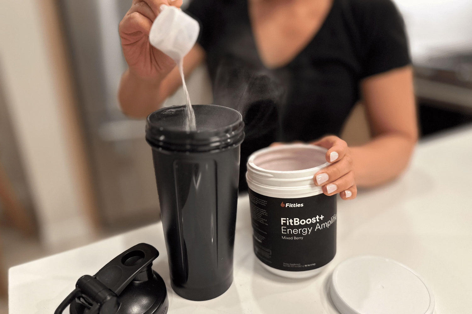 Female pouring scoop of FitBoost+ in shaker