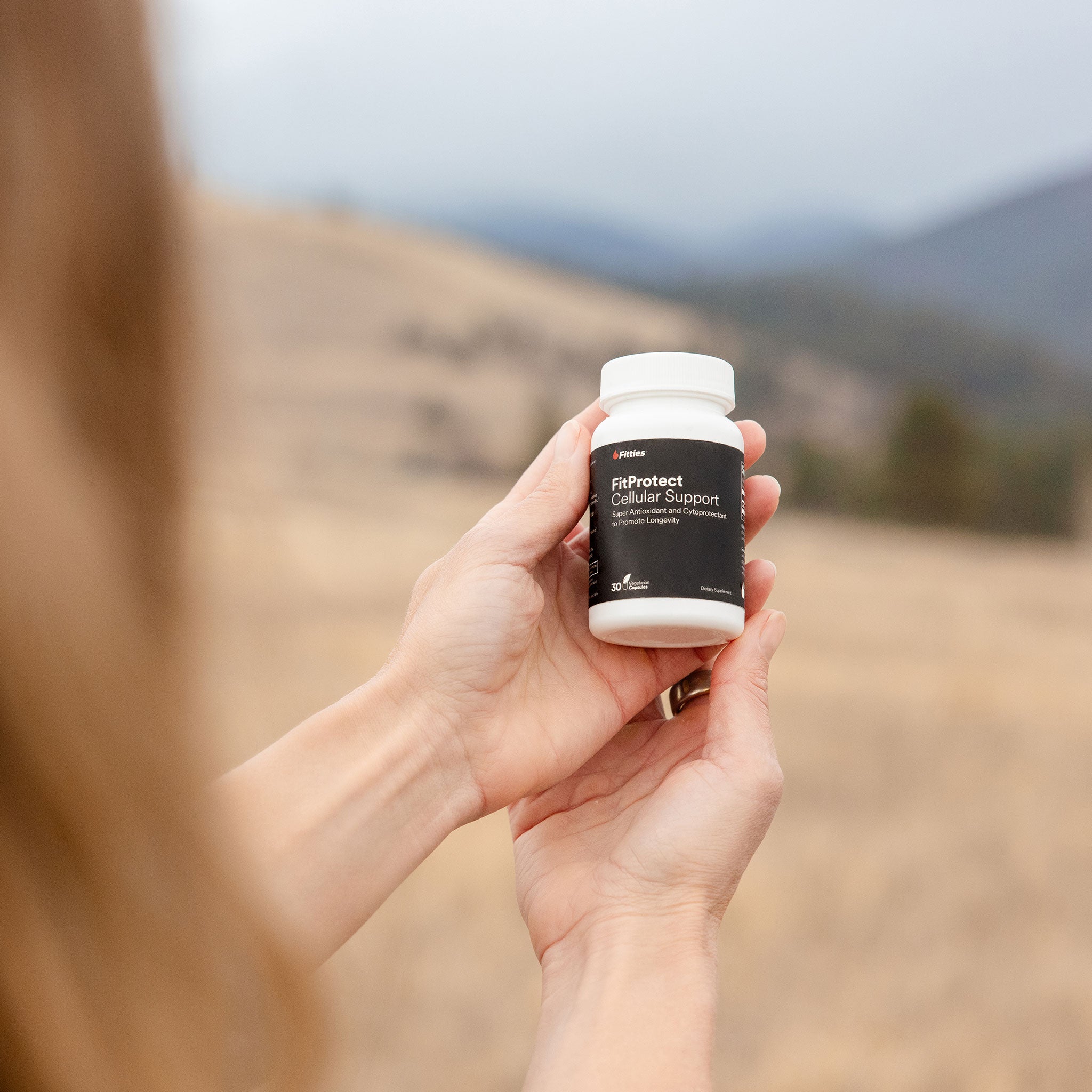 Female athlete holding bottle of Fitties FitProtect outdoors