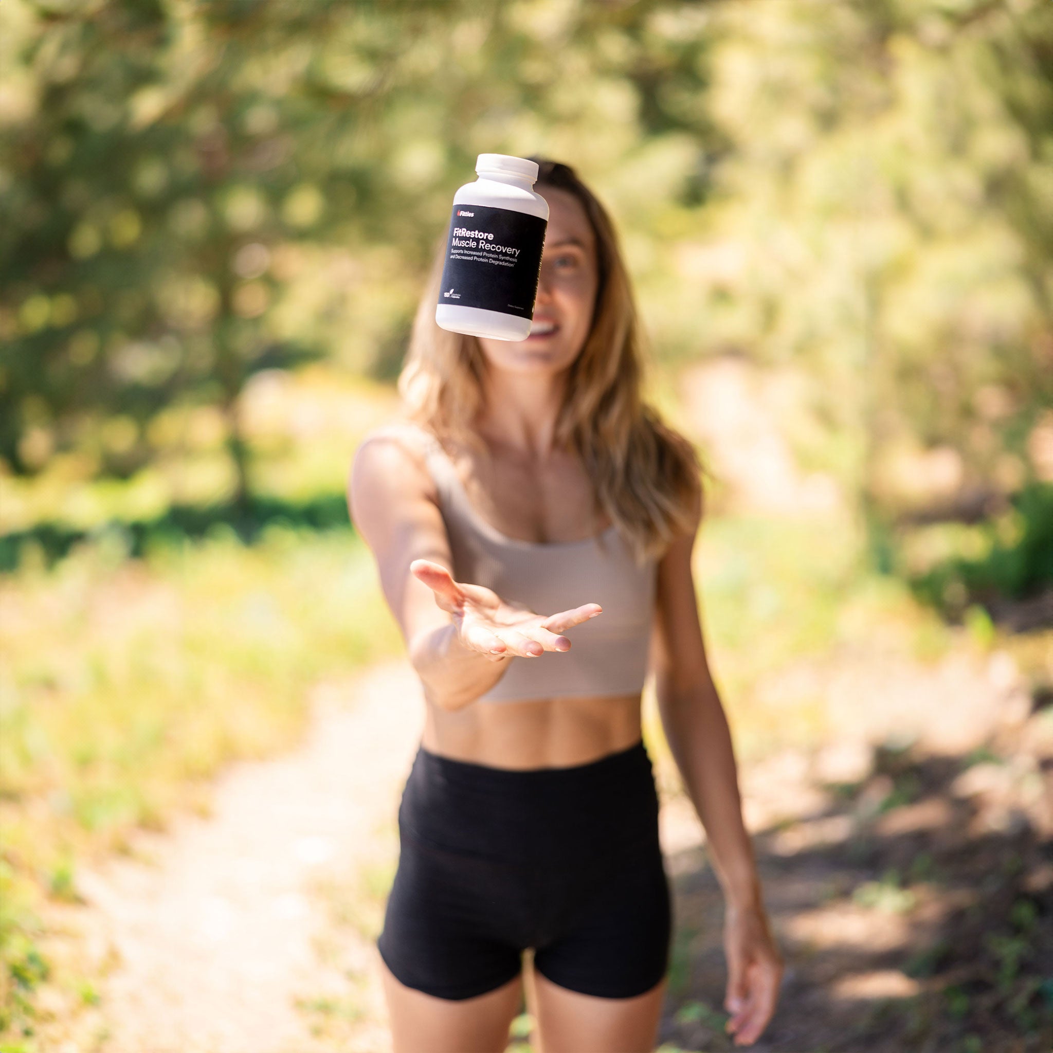 Fitties ambassador catching a bottle of FitRestore outdoors