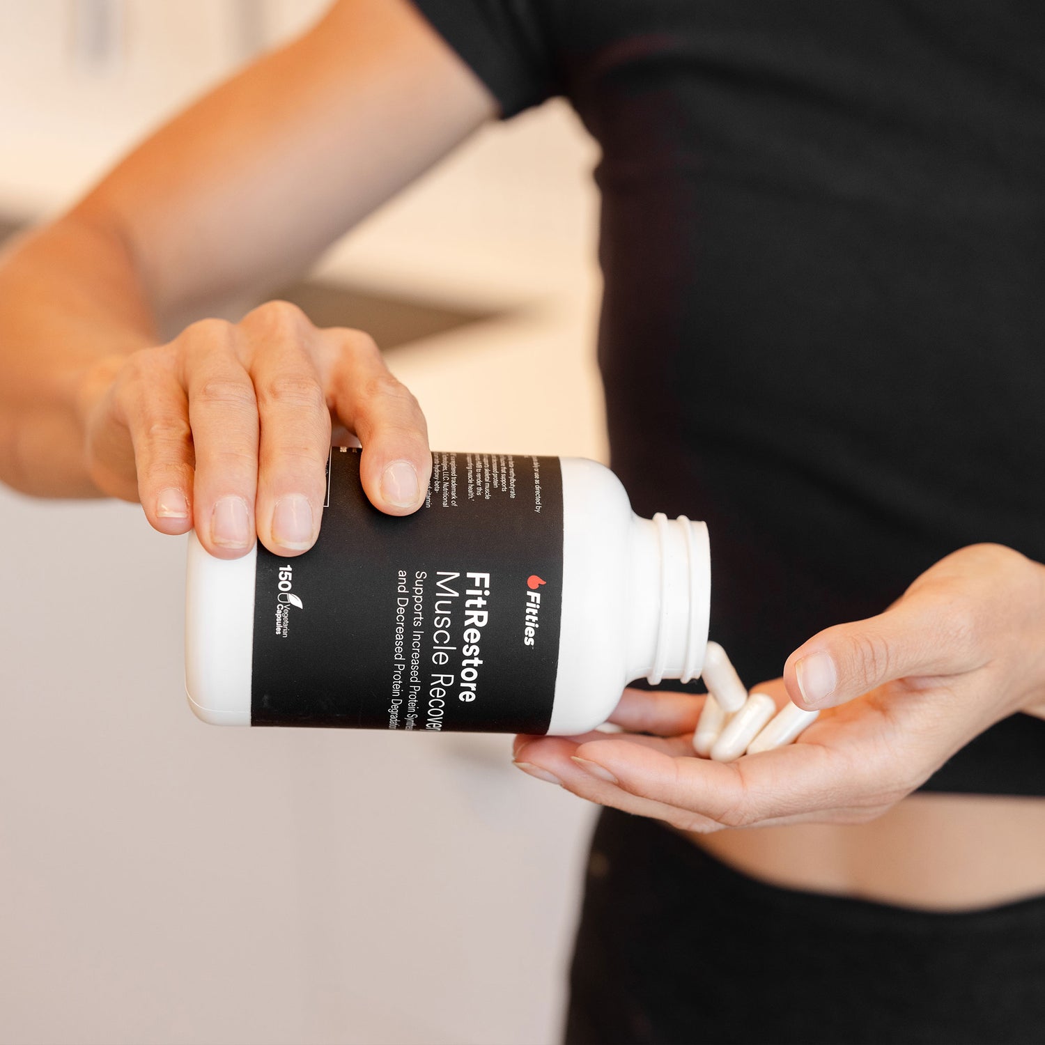 Closeup of bottle and capsules of Fitties FitRestore in hands