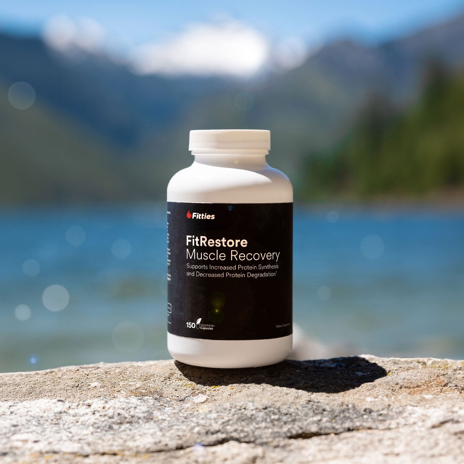 Bottle of Fitties FitRestore with mountains and lake in background