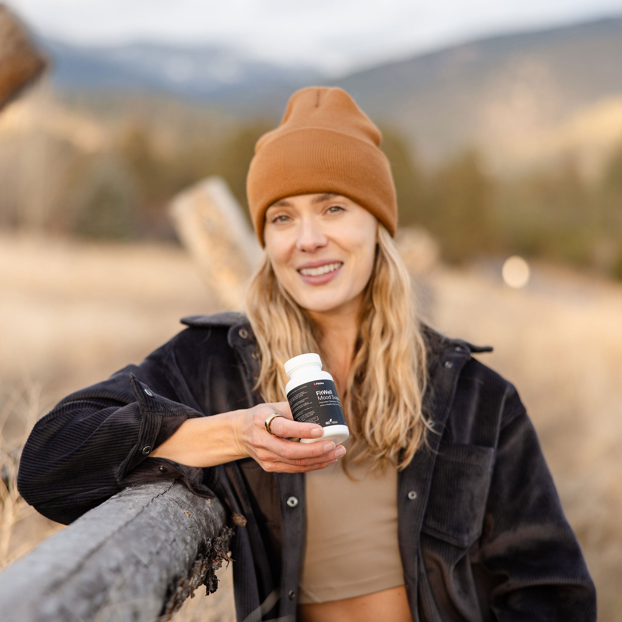 Female athlete in wilderness with bottle of Fitties FitWell