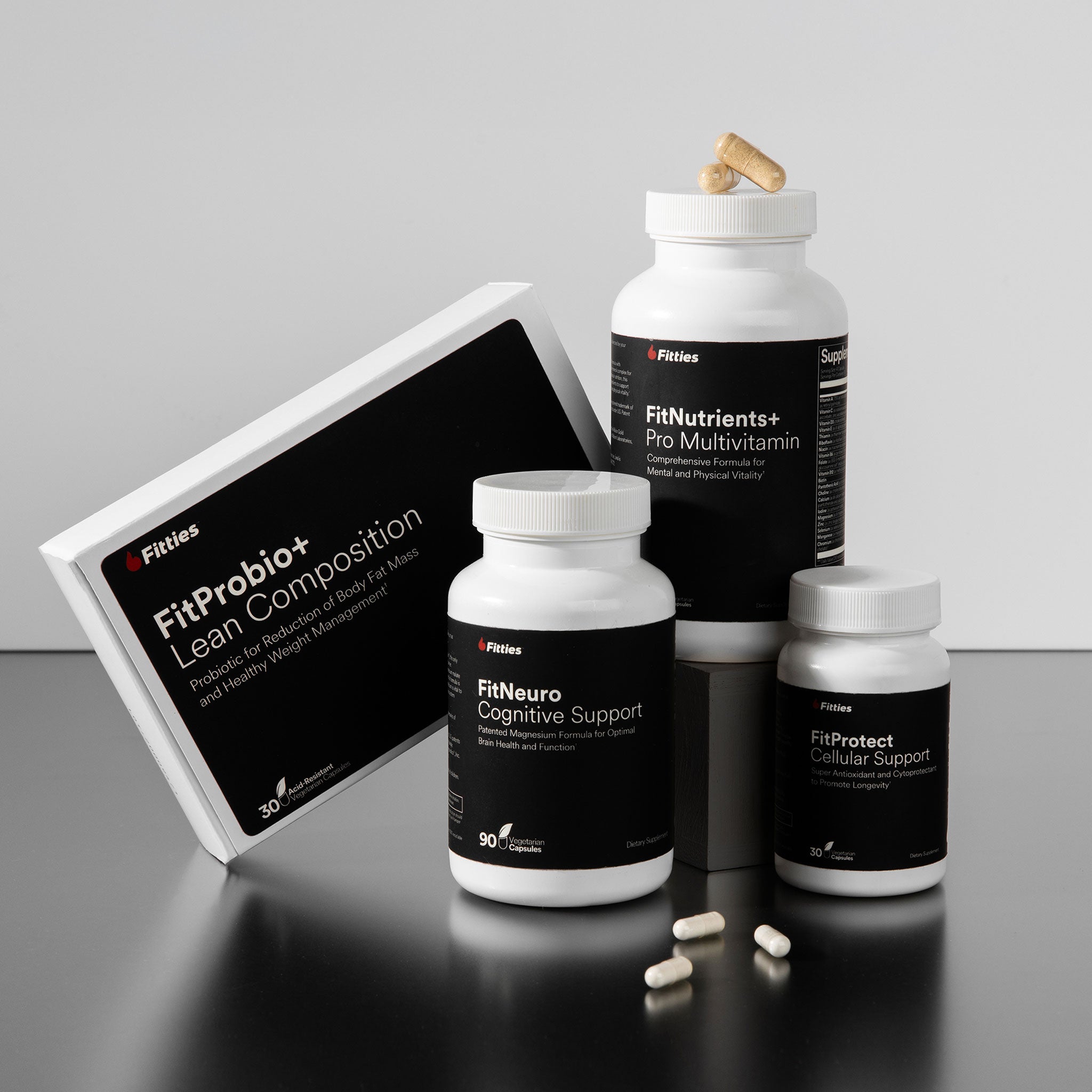 Collection of Fitties supplement containers on a reflective surface with a gray background