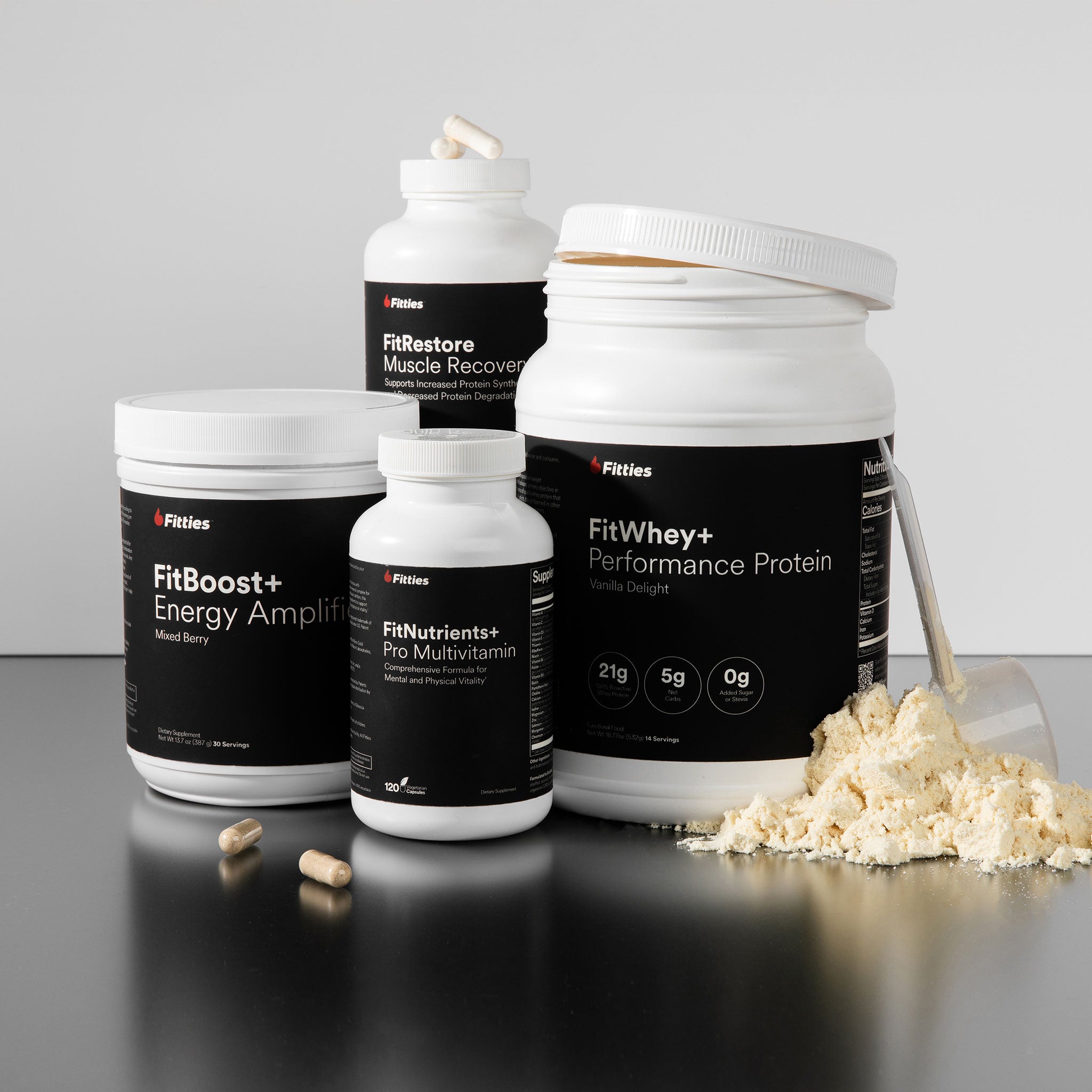 Collection of Fitties supplement containers on a reflective surface with a gray background