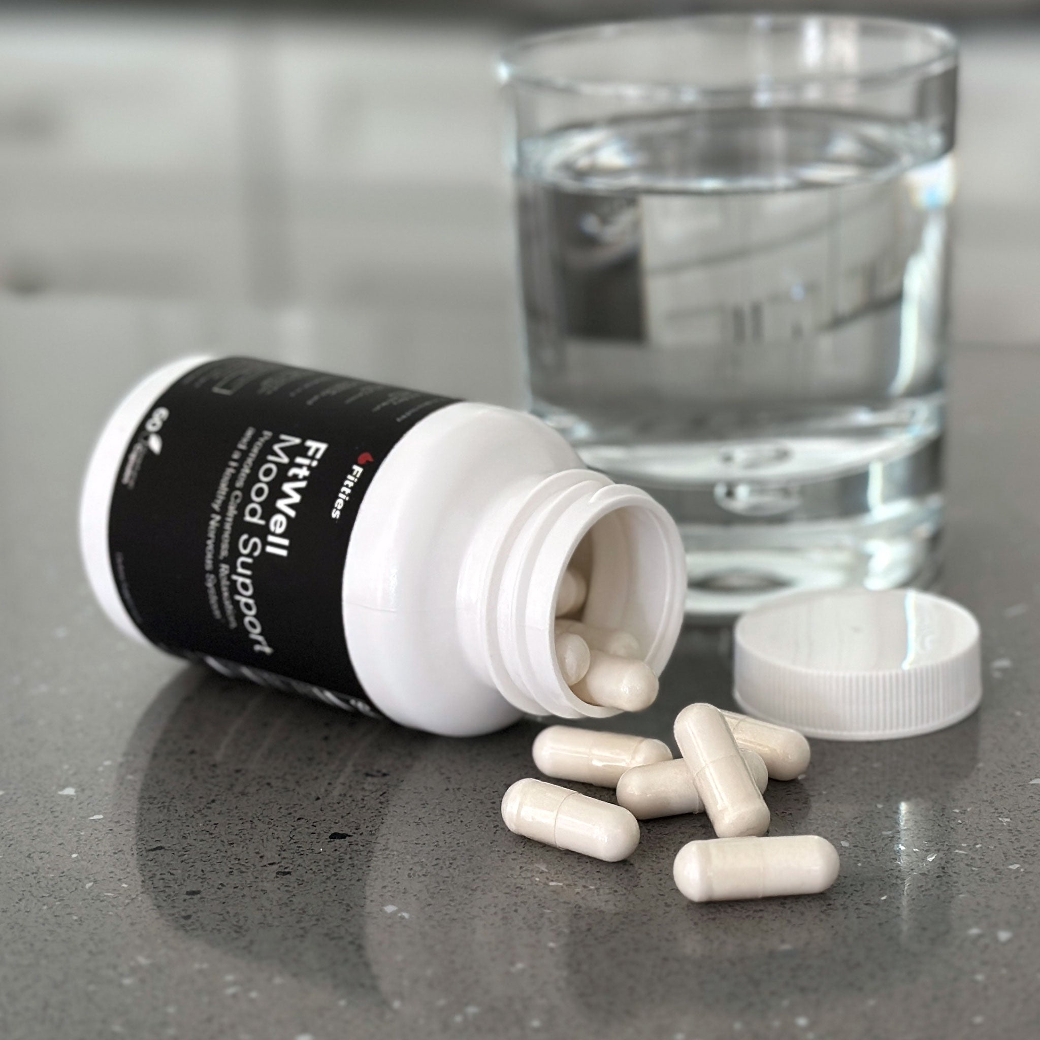 Closeup of FitWell bottle and capsules on kitchen counter