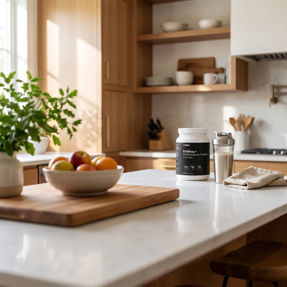 FitWhey+ protein powder sweetened with monk fruit on a kitchen island beside a filled shaker