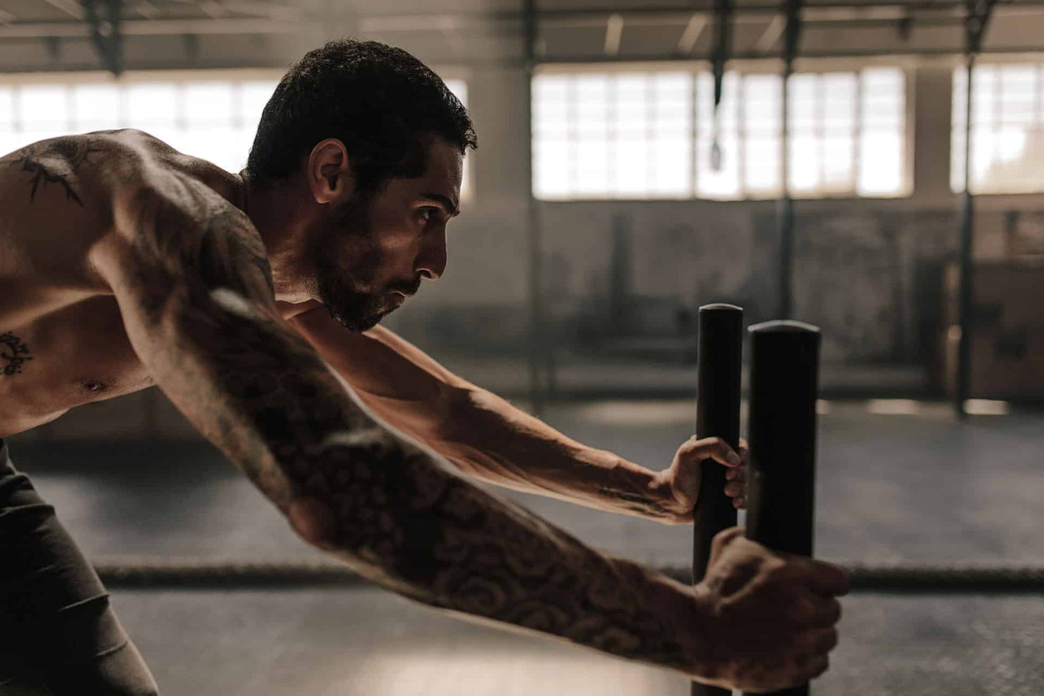 Male pushing weighted sled in warehouse gym