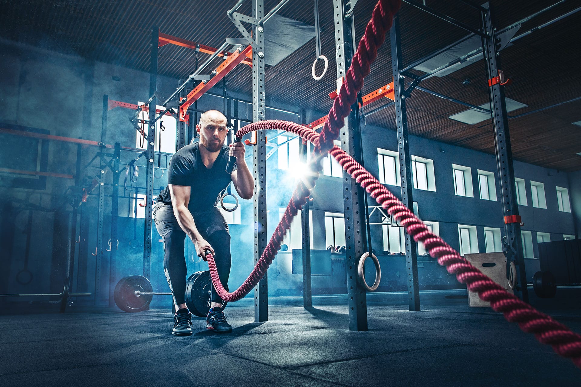 Fit male using battle ropes in gym