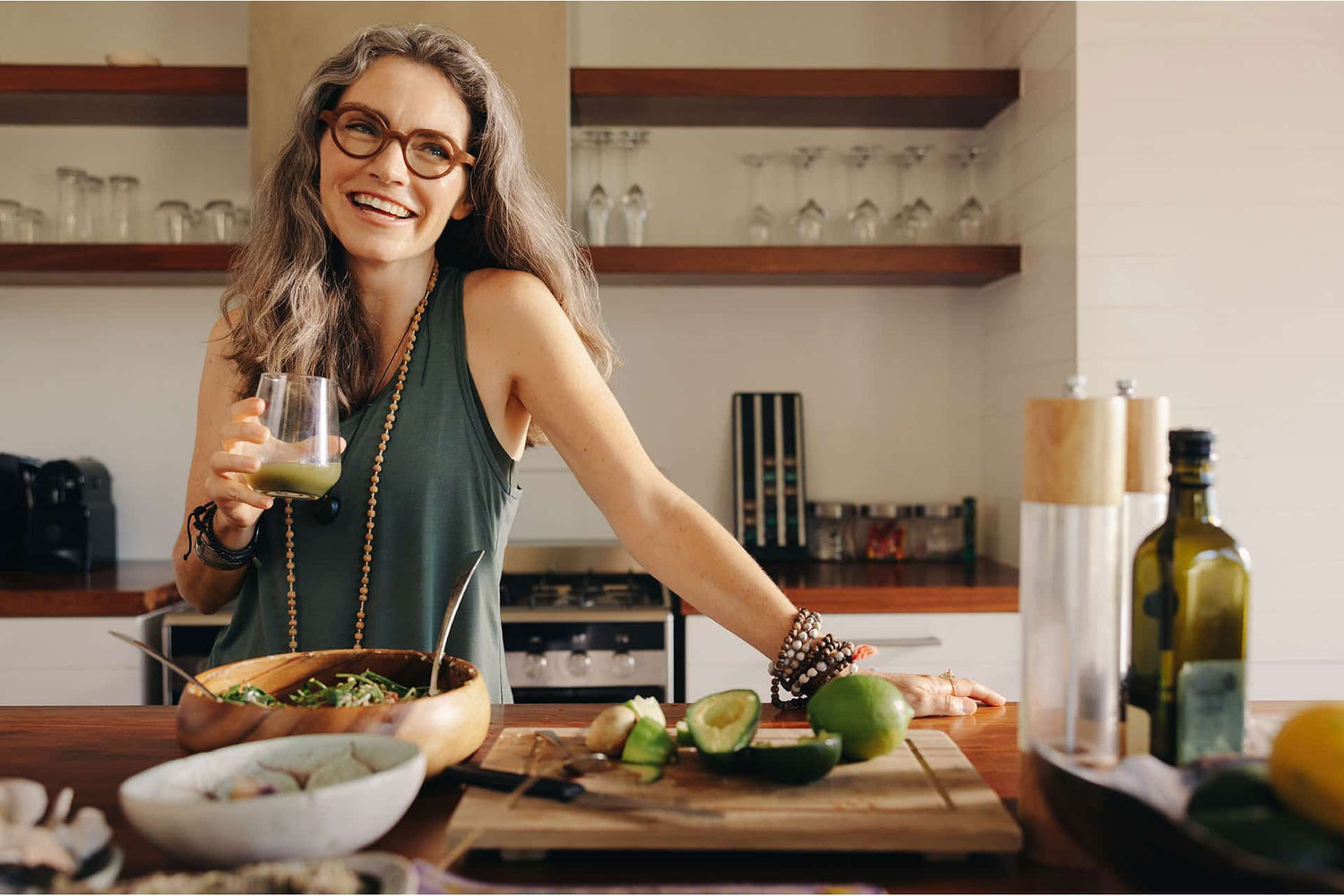 Senior female smiling while enjoying veggie smoothie in kitchen