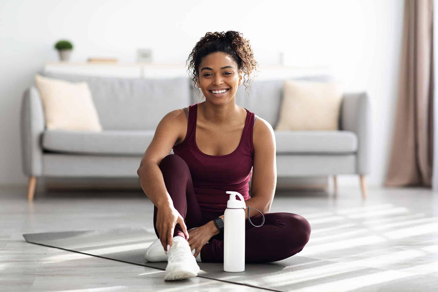 Fit female relaxing on yoga mat after home workout